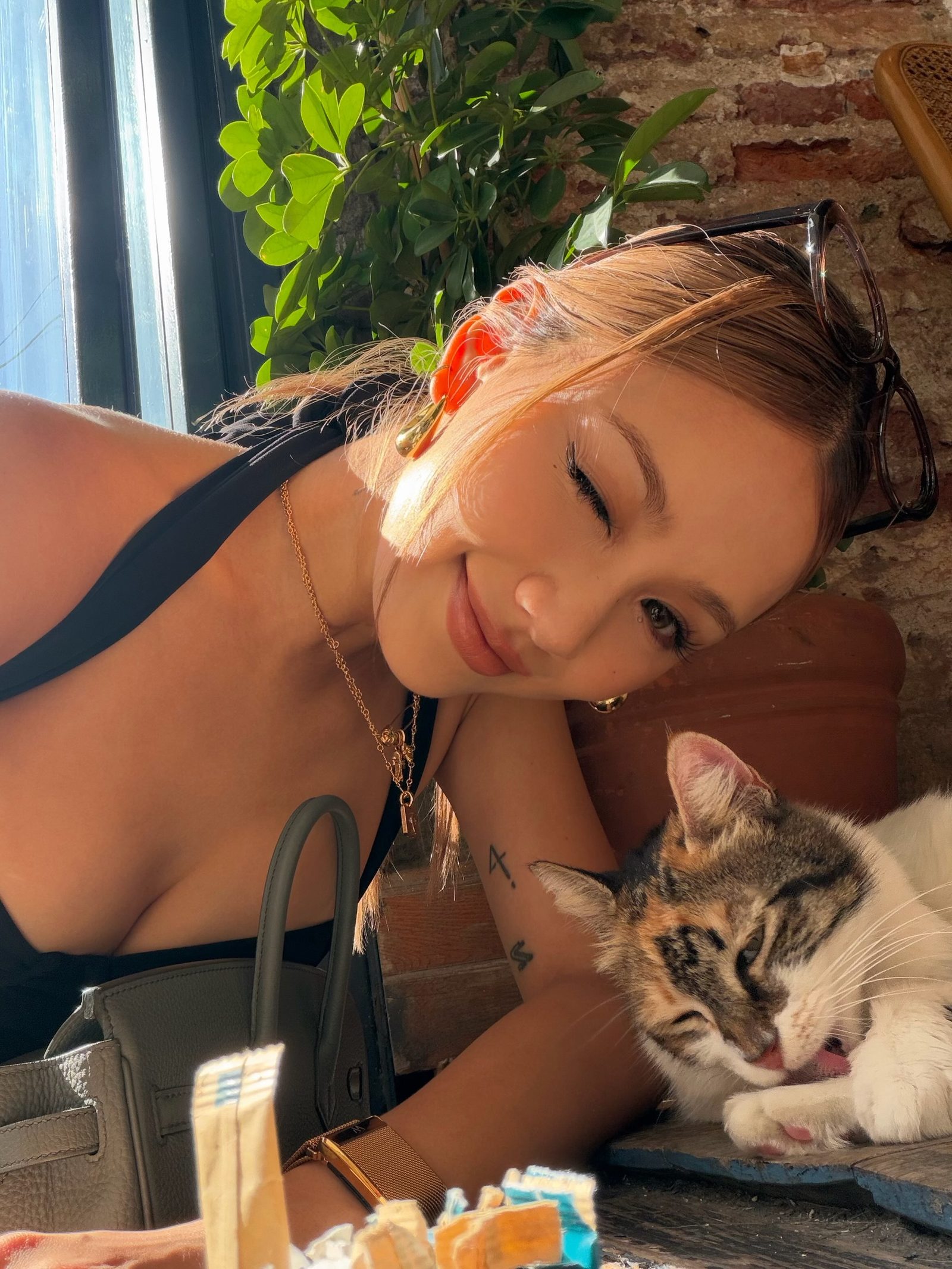 Kathy Zheng winking beside a sleeping cat in a sunny cafe