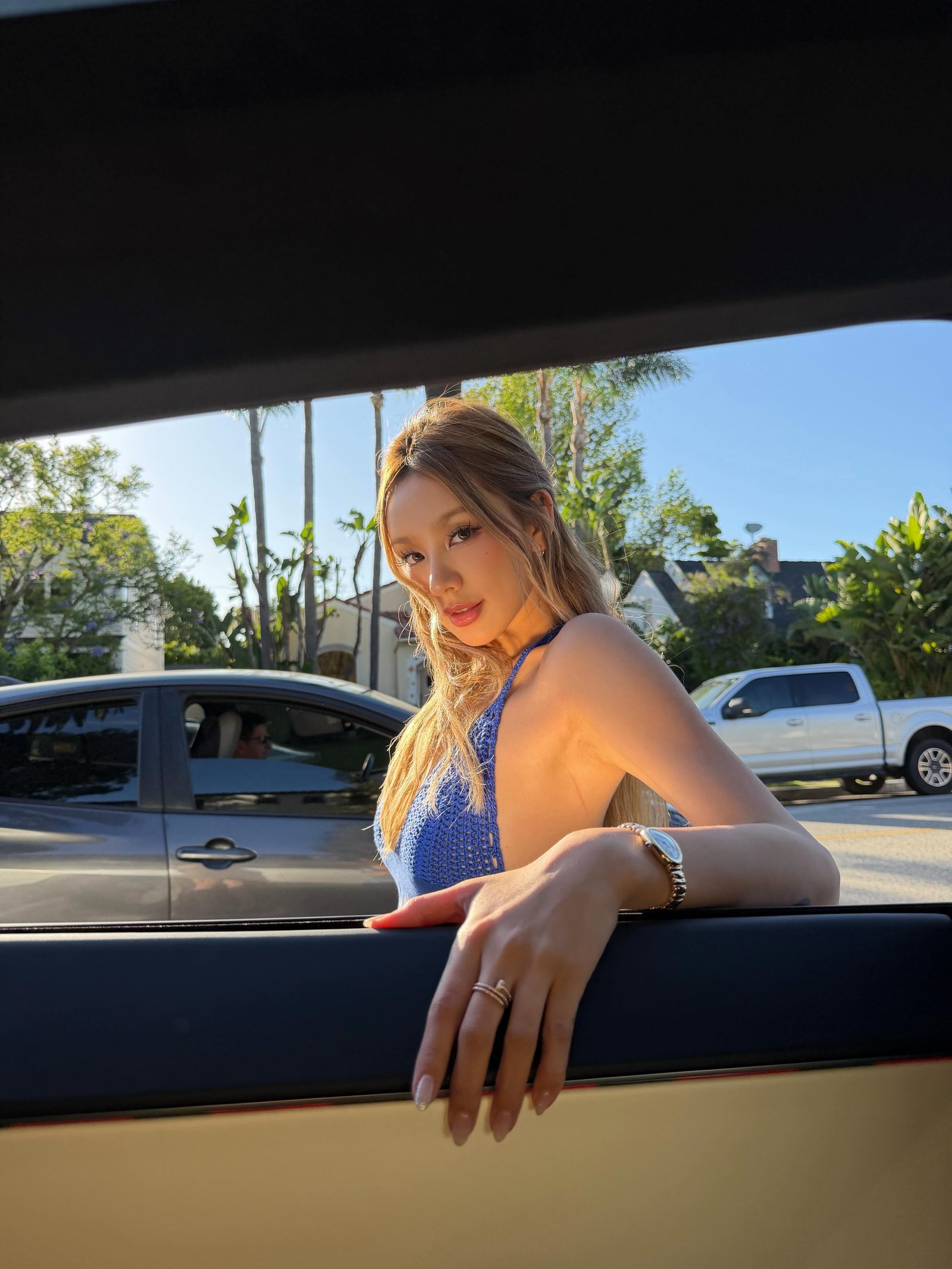Kathy Zheng in blue crochet framed by a car window in golden light