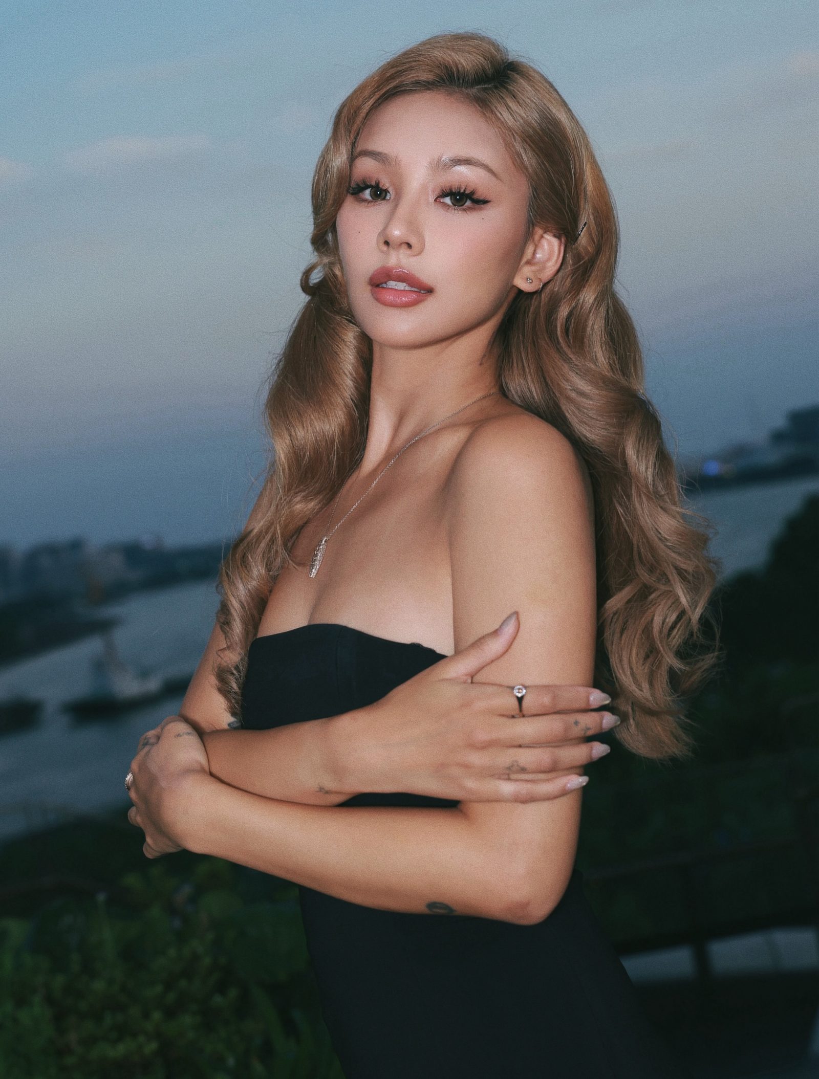 Kathy Zheng in a black strapless dress by the water at dusk