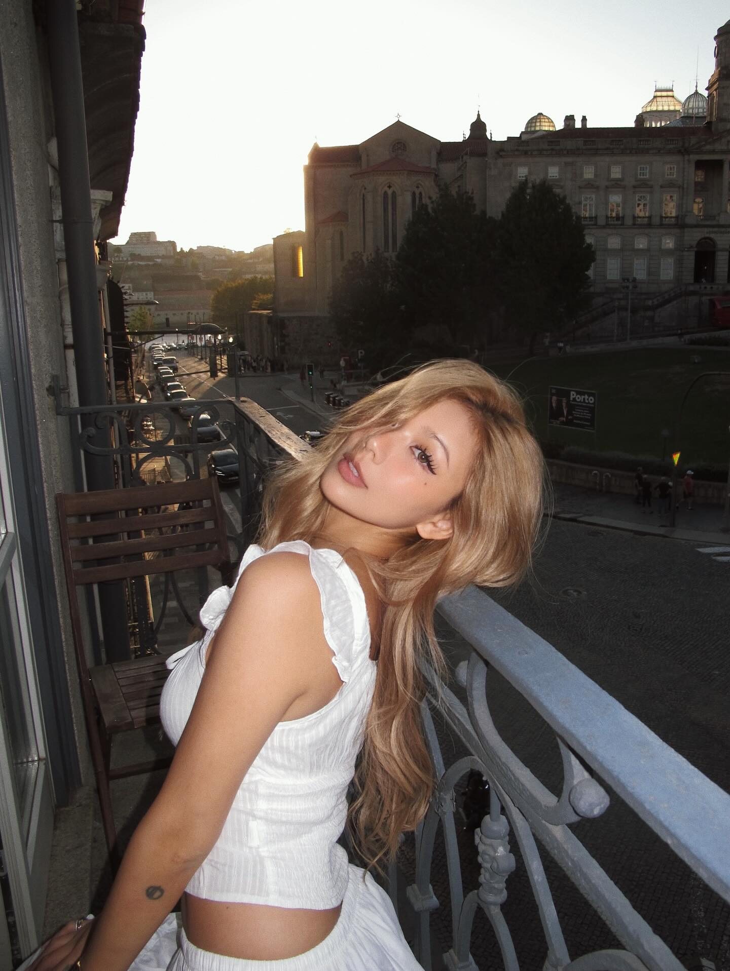 Kathy Zheng leaning on an iron balcony over Porto at dusk