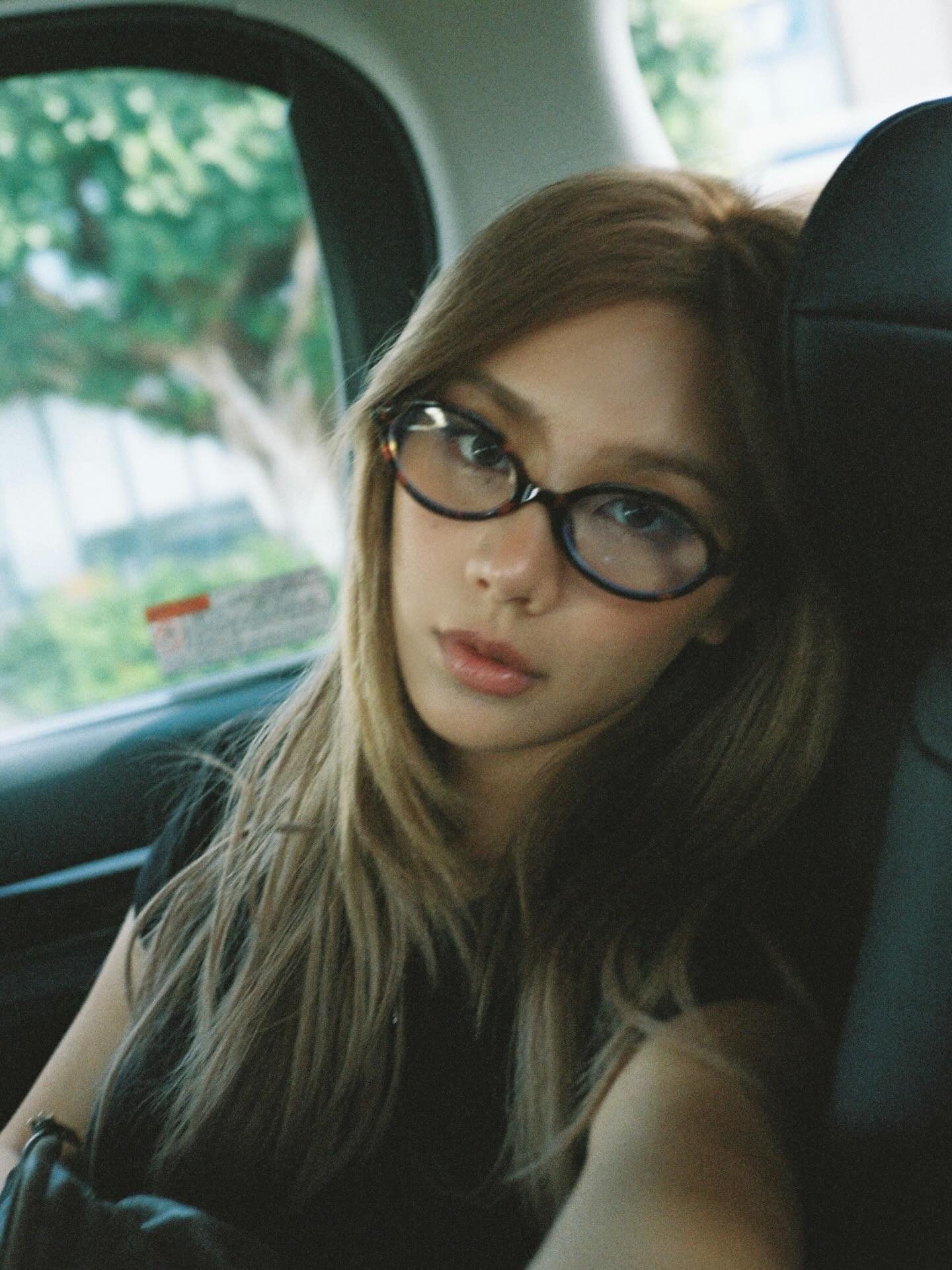 Kathy Zheng in oval glasses, film portrait in a car